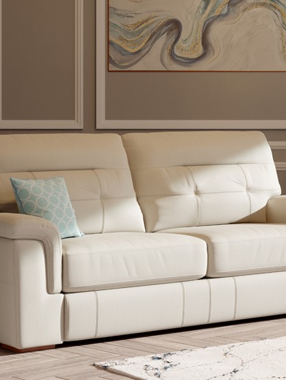 Cream leather sofa shown in a stylish, bright living room with light brown walls and a beige rug